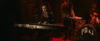 Movie still from “Life Itself” (2018), directed by Dan Fogelman – A woman is playing a keyboard while a man plays a guitar; Medium shot, High angle