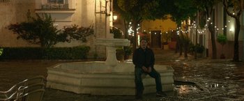Movie still from “Life Itself” (2018), directed by Dan Fogelman – A man sitting in front of a fountain at night; Wide shot, Over the shoulder angle