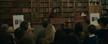 Movie still from “Life Itself” (2018), directed by Dan Fogelman – A woman is speaking in front of an audience in a library; Wide shot, Over the shoulder angle