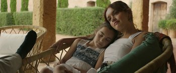 Movie still from “Life Itself” (2018), directed by Dan Fogelman – A woman and a girl sitting next to each other on a porch; Medium shot, High angle