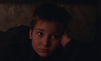 Movie still from “Light of My Life” (2019), directed by Casey Affleck – A young boy is sitting in a dark room; Close Up shot, High angle