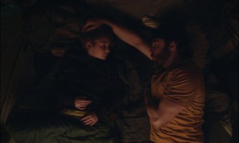 Movie still from “Light of My Life” (2019), directed by Casey Affleck – A man and a boy laying in a bed together; Medium shot, Overhead angle