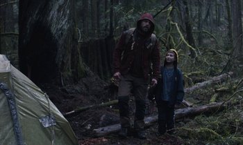Movie still from “Light of My Life” (2019), directed by Casey Affleck – A man and a child are standing in the woods; Wide shot, Over the shoulder angle