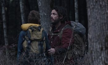 Movie still from “Light of My Life” (2019), directed by Casey Affleck – A man and a boy in the woods with backpacks; Medium shot, Over the shoulder angle