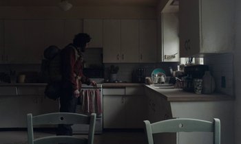 Movie still from “Light of My Life” (2019), directed by Casey Affleck – A man standing in a kitchen next to a stove; Wide shot, Over the shoulder angle