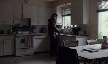 Movie still from “Light of My Life” (2019), directed by Casey Affleck – A man standing in a kitchen next to a sink; Wide shot, Low angle