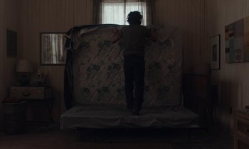 Movie still from “Light of My Life” (2019), directed by Casey Affleck – A person standing on a bed in a room; Wide shot, Low angle