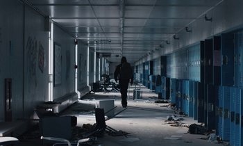Movie still from “Light of My Life” (2019), directed by Casey Affleck – A person walking down a hallway in a building; Extreme Wide shot, Low angle