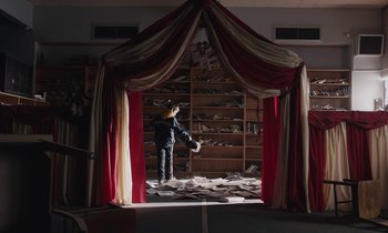 Movie still from “Light of My Life” (2019), directed by Casey Affleck – A man standing in front of a bookcase filled with books; Wide shot, Low angle