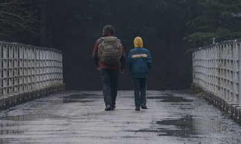Movie still from “Light of My Life” (2019), directed by Casey Affleck – A man and a child walking down a wet road; Wide shot, Over the shoulder angle
