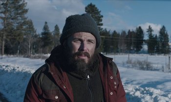 Movie still from “Light of My Life” (2019), directed by Casey Affleck – A man with a beard wearing a red jacket and a gray hat; Medium shot, Low angle