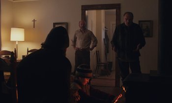 Movie still from “Light of My Life” (2019), directed by Casey Affleck – A group of people standing around a living room; Medium shot, Low angle