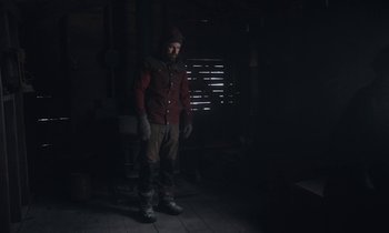 Movie still from “Light of My Life” (2019), directed by Casey Affleck – A man standing in a dark room wearing boots and a hat; Wide shot, Low angle