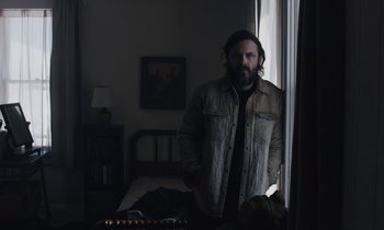 Movie still from “Light of My Life” (2019), directed by Casey Affleck – A man standing next to a window in a room; Medium shot, Low angle