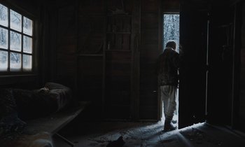 Movie still from “Light of My Life” (2019), directed by Casey Affleck – An old man standing in a room looking out a window; Wide shot, Over the shoulder angle
