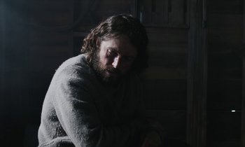 Movie still from “Light of My Life” (2019), directed by Casey Affleck – A man with long hair sitting in a dark room; Close Up shot, Over the shoulder angle