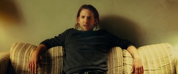 Movie still from “Limitless” (2011), directed by Neil Burger – A man sitting on a couch in a room; Medium shot, Low angle