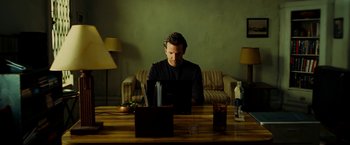 Movie still from “Limitless” (2011), directed by Neil Burger – A man sitting in front of a laptop computer on top of a wooden table; Medium shot, High angle