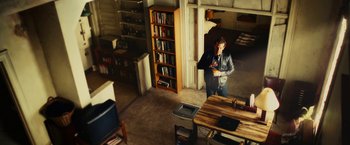 Movie still from “Limitless” (2011), directed by Neil Burger – A person standing in a room with a book shelf in front of them; Wide shot, High angle