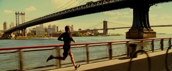 Movie still from “Limitless” (2011), directed by Neil Burger – A man running on a bridge near the water; Wide shot, High angle