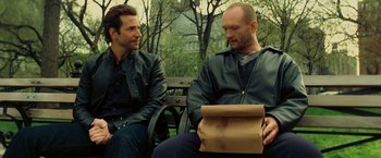 Movie still from “Limitless” (2011), directed by Neil Burger – Two men sitting on a park bench one is holding a paper bag; Medium shot, Over the shoulder angle