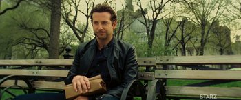 Movie still from “Limitless” (2011), directed by Neil Burger – A man sitting on top of a wooden park bench; Medium shot, Over the shoulder angle