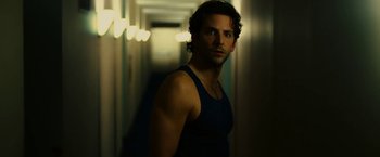 Movie still from “Limitless” (2011), directed by Neil Burger – A man in a black tank top standing in a hallway; Medium shot, Over the shoulder angle