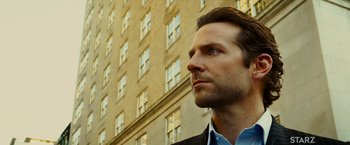 Movie still from “Limitless” (2011), directed by Neil Burger – A person wearing a suit near a building; Close Up shot, Low angle