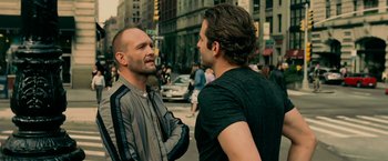 Movie still from “Limitless” (2011), directed by Neil Burger – Two men talking on the sidewalk of a busy city street; Medium shot, Over the shoulder angle