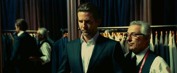 Movie still from “Limitless” (2011), directed by Neil Burger – A man wearing a suit and tie standing in front of a rack of suits; Medium shot, Low angle