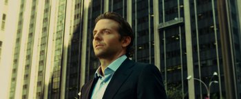 Movie still from “Limitless” (2011), directed by Neil Burger – A person wearing a suit near a building; Close Up shot, Low angle