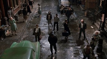 Movie still from “Little Shop of Horrors” (1986), directed by Frank Oz – A group of people walking down a wet street; Wide shot, High angle