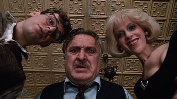 Movie still from “Little Shop of Horrors” (1986), directed by Frank Oz – A man and two women posing for a picture with another man; Close Up shot, Low angle