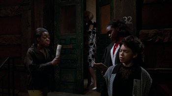 Movie still from “Little Shop of Horrors” (1986), directed by Frank Oz – A group of people standing in front of a door; Medium shot, High angle