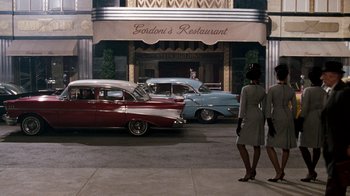 Movie still from “Little Shop of Horrors” (1986), directed by Frank Oz – A couple of cars parked on the side of a road; Wide shot, High angle