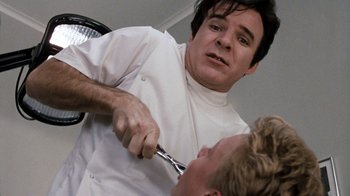 Movie still from “Little Shop of Horrors” (1986), directed by Frank Oz – A man in a chef's outfit cutting another man's hair; Close Up shot, Over the shoulder angle