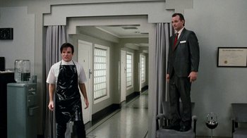 Movie still from “Little Shop of Horrors” (1986), directed by Frank Oz – A man in a suit standing next to another man in a suit; Wide shot, Low angle