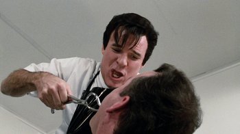 Movie still from “Little Shop of Horrors” (1986), directed by Frank Oz – A man with a pair of shears on his face; Close Up shot, Over the shoulder angle
