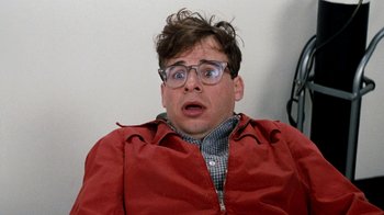Movie still from “Little Shop of Horrors” (1986), directed by Frank Oz – A man in a red jacket with glasses and a surprised look on his face; Close Up shot, Overhead angle