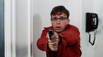 Movie still from “Little Shop of Horrors” (1986), directed by Frank Oz – A man in a red jacket holding a gun in his hand; Close Up shot, Low angle
