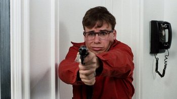 Movie still from “Little Shop of Horrors” (1986), directed by Frank Oz – A man holding a gun in a room; Close Up shot, Low angle