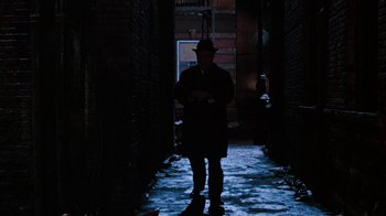 Movie still from “Little Shop of Horrors” (1986), directed by Frank Oz – A man standing in the dark in a dark alley; Wide shot, Low angle