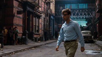 Movie still from “Little Shop of Horrors” (1986), directed by Frank Oz – A man walking down the street wearing a blue shirt; Medium shot, Low angle