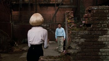 Movie still from “Little Shop of Horrors” (1986), directed by Frank Oz – A man and a woman are standing in an alleyway; Wide shot, Over the shoulder angle