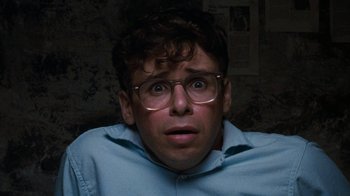 Movie still from “Little Shop of Horrors” (1986), directed by Frank Oz – A young man with glasses is looking surprised; Close Up shot, Overhead angle