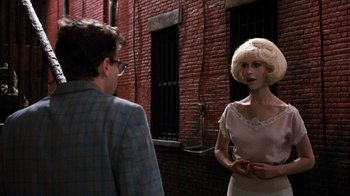 Movie still from “Little Shop of Horrors” (1986), directed by Frank Oz – A man and a woman standing next to each other in front of a brick building; Medium shot, Over the shoulder angle