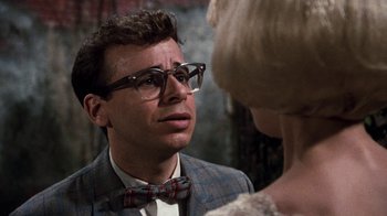 Movie still from “Little Shop of Horrors” (1986), directed by Frank Oz – A man wearing glasses and a bow tie talking to a woman; Close Up shot, Over the shoulder angle