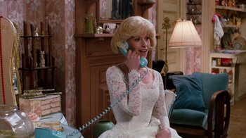Movie still from “Little Shop of Horrors” (1986), directed by Frank Oz – A woman in a white dress talking on a phone; Medium shot, Over the shoulder angle