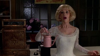 Movie still from “Little Shop of Horrors” (1986), directed by Frank Oz – A woman in a white dress pouring a drink; Medium shot, Low angle