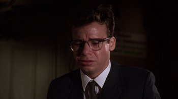 A man in a suit and glasses is crying